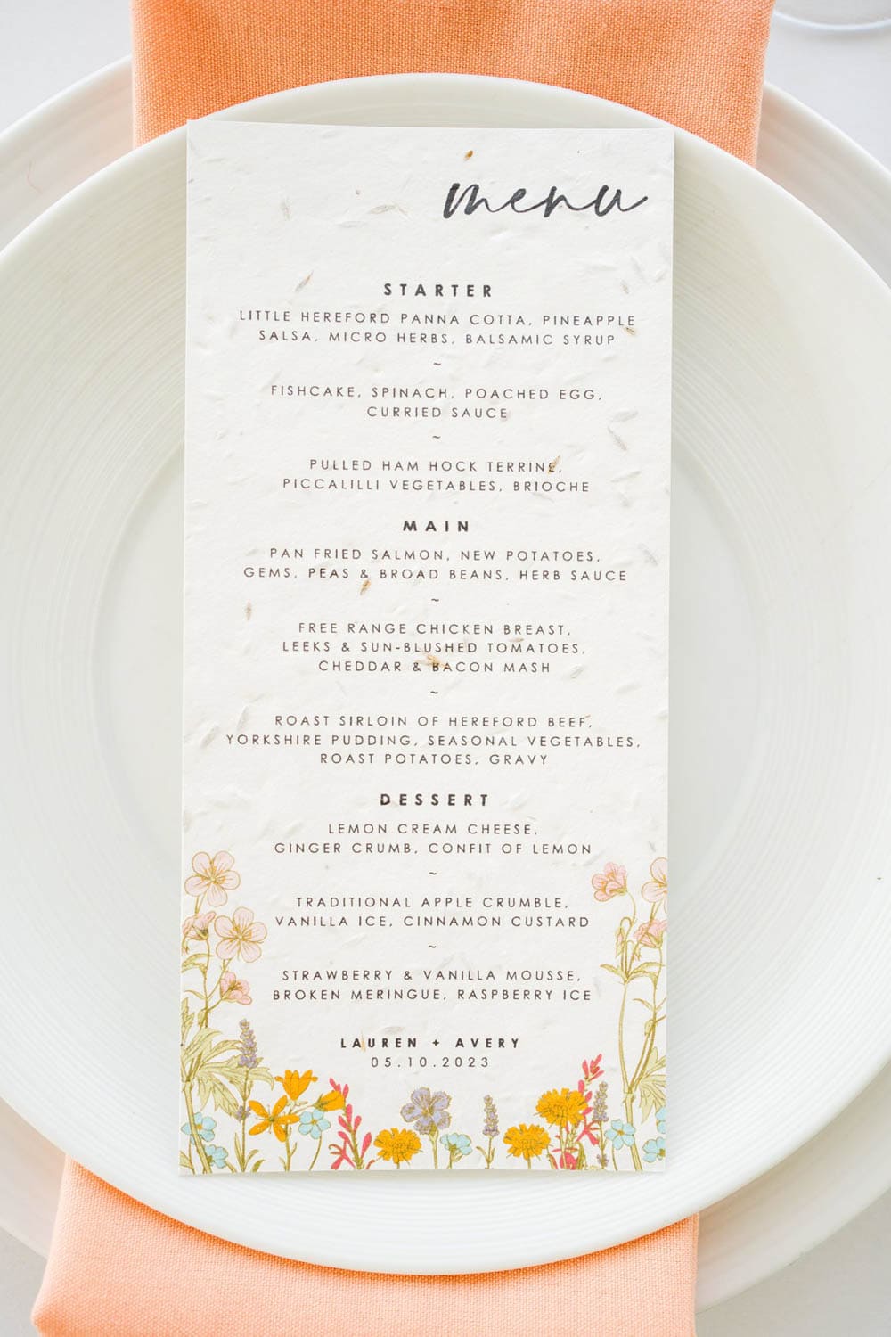 A wedding menu featuring starters, mains, and desserts, with floral illustrations at the bottom and the names Lauren and Avery and the date 05.10.2023 at the bottom.